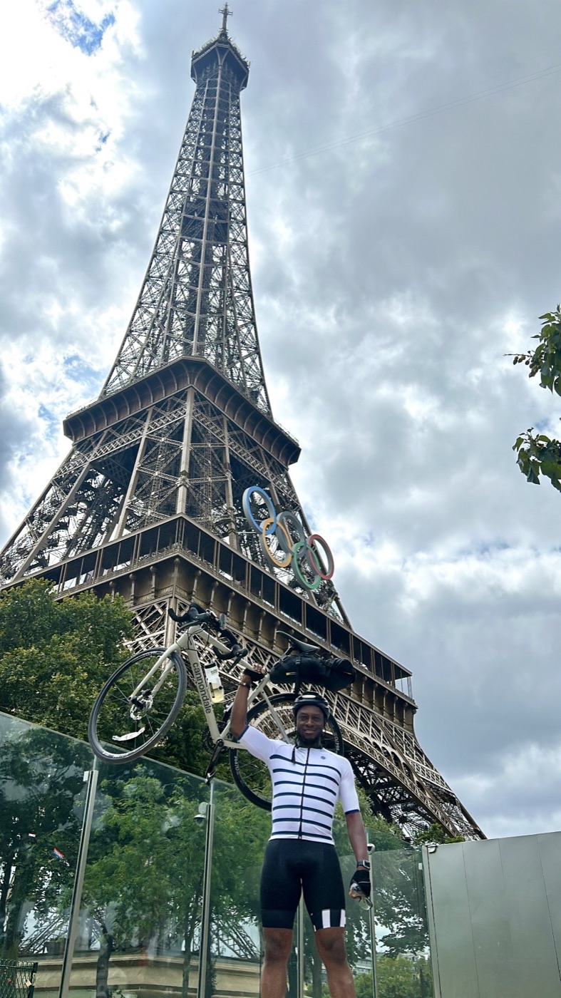 Allen holding his bicycle, Red, in front of the Eiffel Tower after cycling from London to Paris
